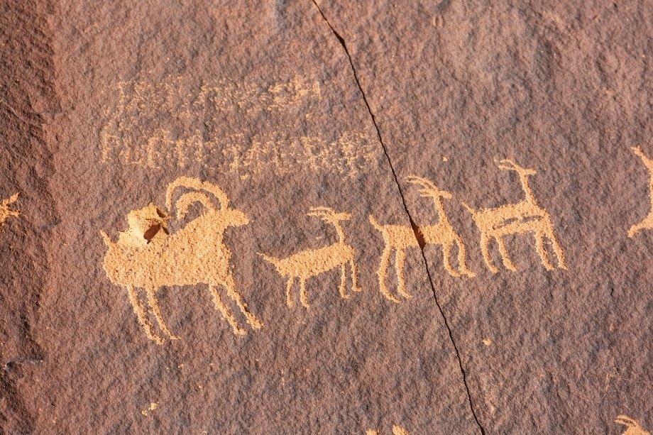 Ancient Southwest Native American art history petroglyphs carved into a red sandstone rock face.