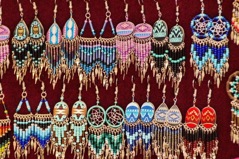 A vibrant retail display hanging rows of handmade Native American beaded fringe earrings.