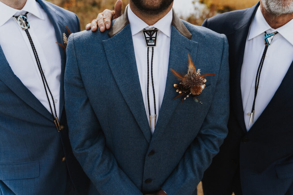 Three men wearing modern Western suits adorned with authentic Native American turquoise bolo ties.
