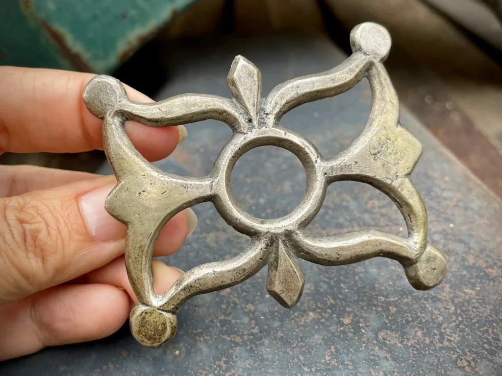An unpolished, heavy Navajo sandcast belt buckle showing traditional Southwestern metalwork motifs.
